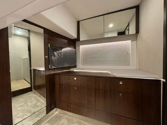 Modern bathroom interior featuring dark wood cabinetry, a mirror, and a window with blinds. Stylish and contemporary design.